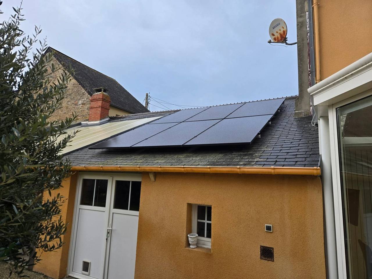 Panneaux solaires sur toit ardoise d'une maison orange